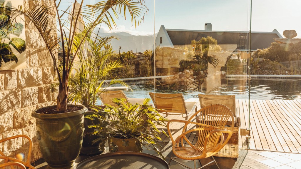 A cottage patio and pool at Babylonstoren, looking out to whitewashed Cape Dutch buildings and the mountains